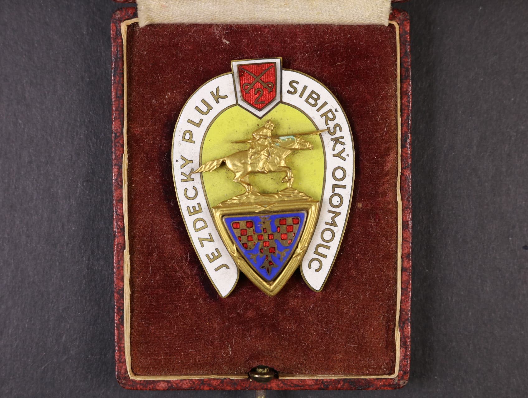 Odznak 2. jezdeckého pluku Sibiřského Olomouc, na reversu značka výrobce Karnet Kyselý Praha, upínání na vodorovnou jehlu, 56,5x43 mm, originální etue