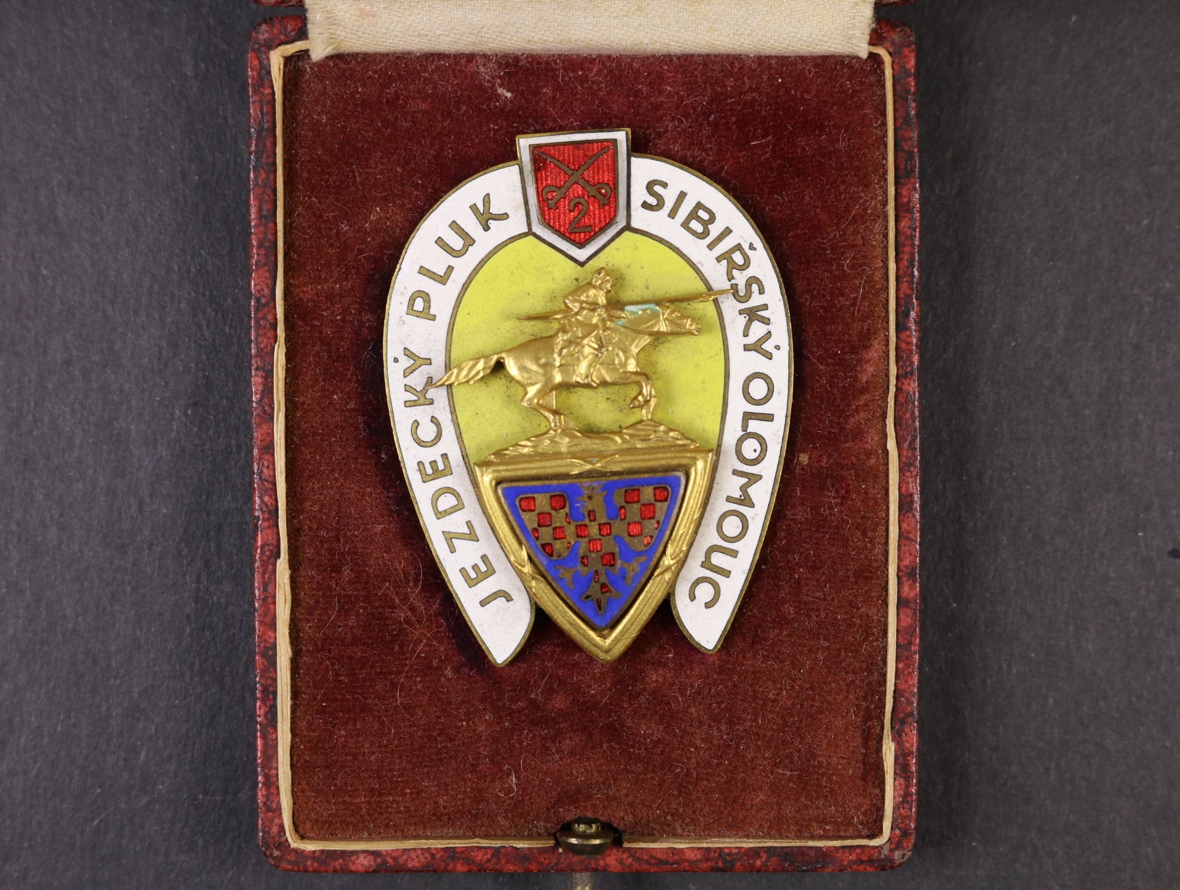 Odznak 2. jezdeckého pluku Sibiřského Olomouc, na reversu značka výrobce Karnet Kyselý Praha, upínání na vodorovnou jehlu, 56,5x43 mm, originální etue